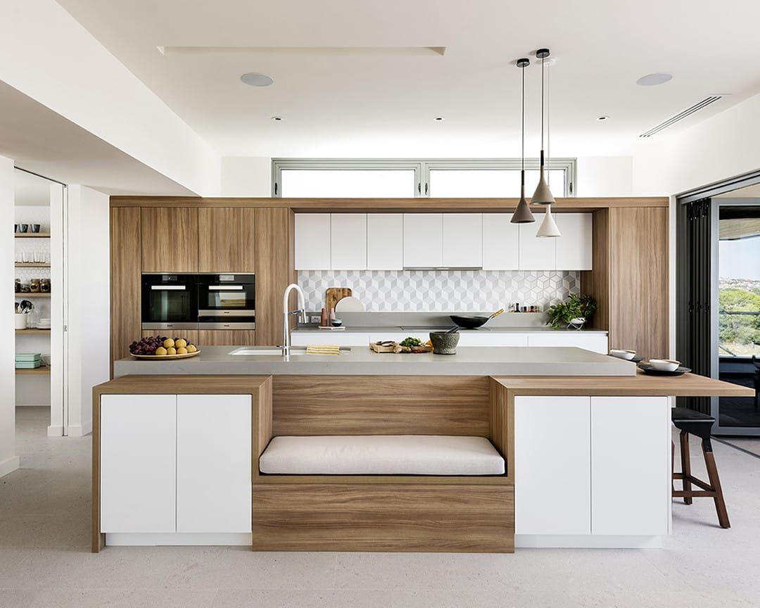 White and timber kitchen cabinets with a concrete-effect quartz island worktop and a built-in bench seat