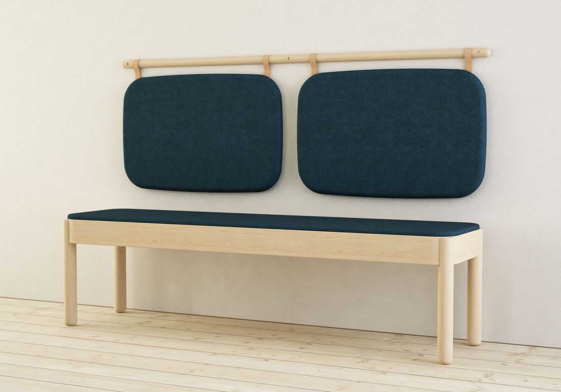 A pale timber wall bench with two dark blue upholstered back pads hung on a rail