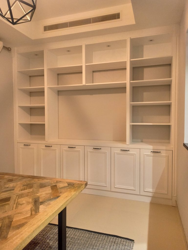 White built-in media wall with open shelving and shaker-style cupboards in a home renovation