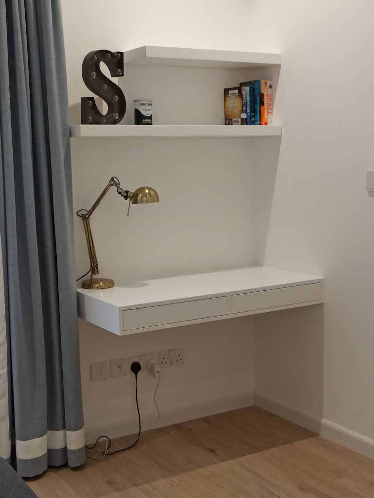 Floating wall-mounted desk with drawers and matching shelves above, fitted in a study