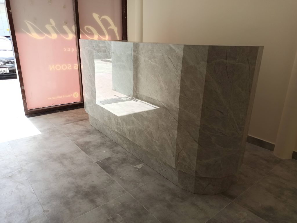 A curved stone-clad reception counter designed for a Dubai office reception